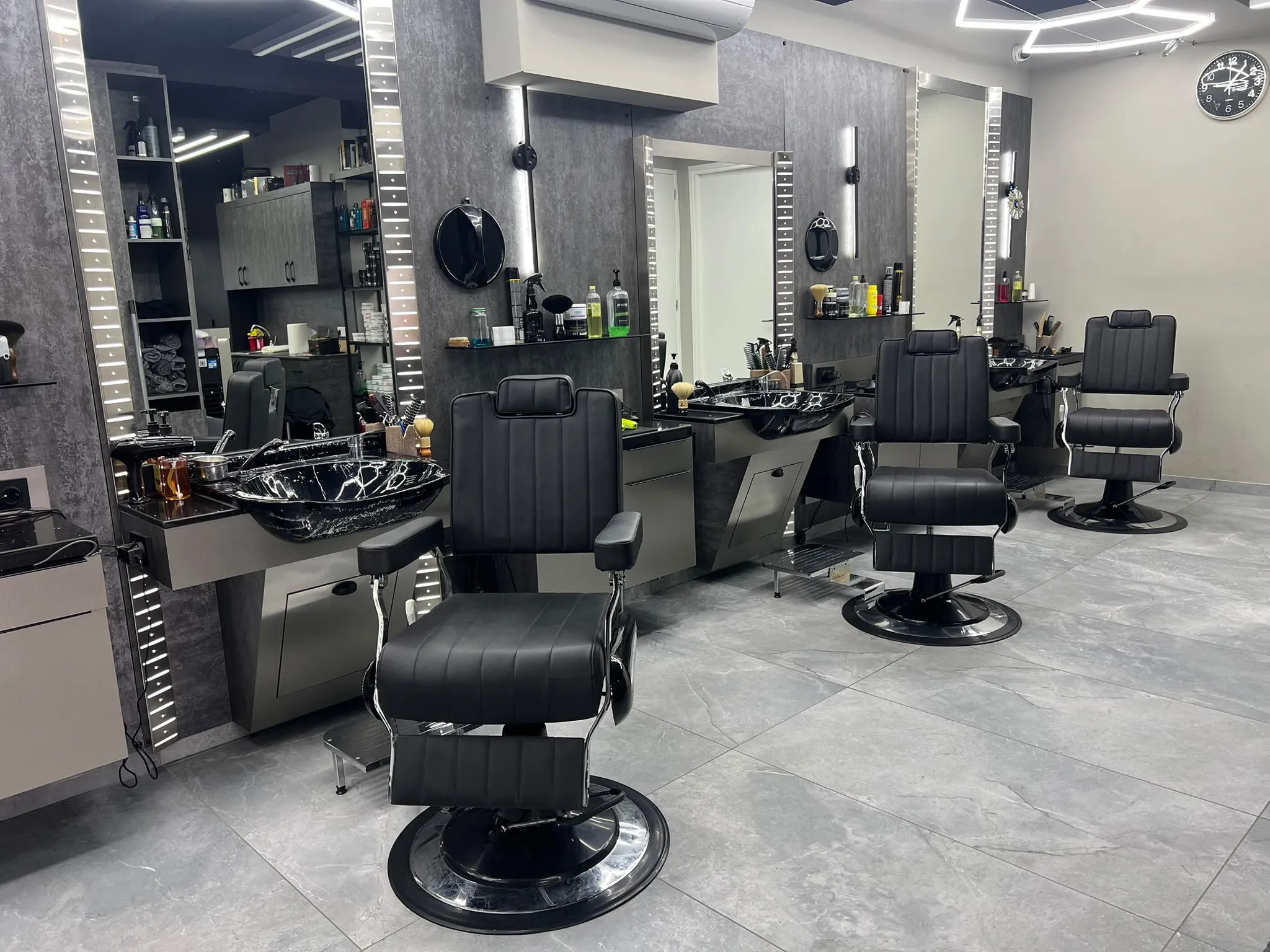 De rij knipstoelen en verlichte spiegels in de salon van Kapper Vedat